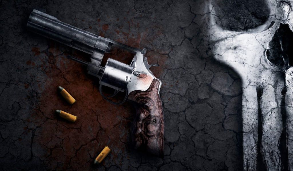 A stark and unsettling image, suggestive of themes often associated with serial killers, features a revolver and three bullet casings lying on a dark, cracked, and blood-splattered surface. The revolver, with a metallic finish and a wooden grip, is positioned diagonally on the left. To the right, a large, prominent skull motif, resembling that of The Punisher, is partially visible, blending into the textured, cracked background. The overall impression is one of violence and a grim atmosphere.