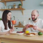a couple eating a simple healthy breakfast with not too many food on the table