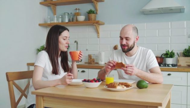 a couple eating a simple healthy breakfast with not too many food on the table