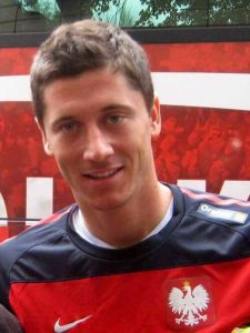 Portrait of a young Robert Lewandowski smiling while wearing the red Poland National Team training jersey in 2011.
