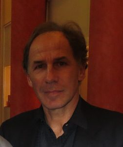Close-up portrait of Franco Baresi, one of football's legendary captains, wearing a dark collared shirt and looking directly at the camera against a reddish background.