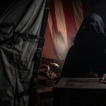 A shadowy, mysterious figure claiming to be the dead Emperor sits completely obscured in darkness